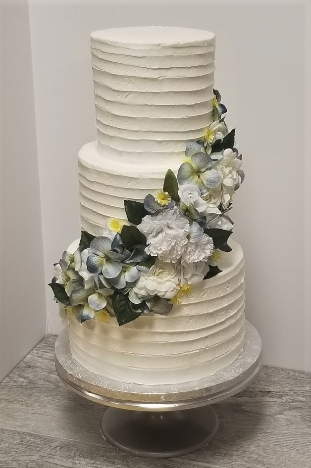 Three-tier white wedding cake decorated with sugar flowers